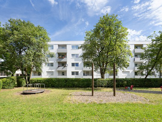 Wohngebäude mit Balkonen ausgerichtet auf eine Grünanlage mit Spielplatz